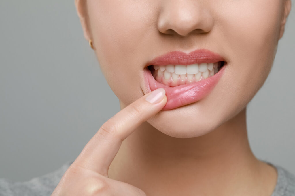 Woman showing healthy gums on grey background, closeup